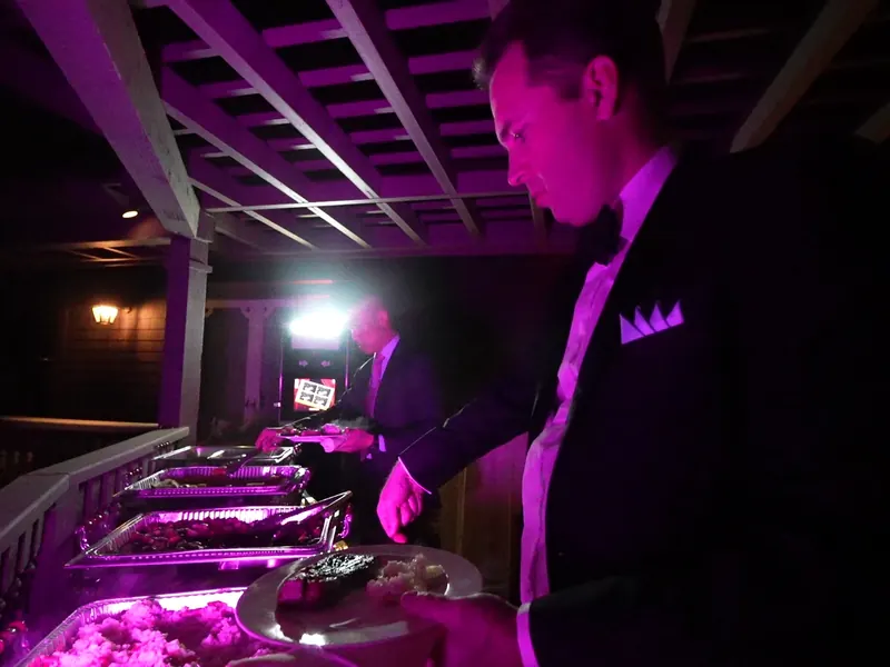 Server tending chafing dishes under colored uplighting at an evening Dublin reception