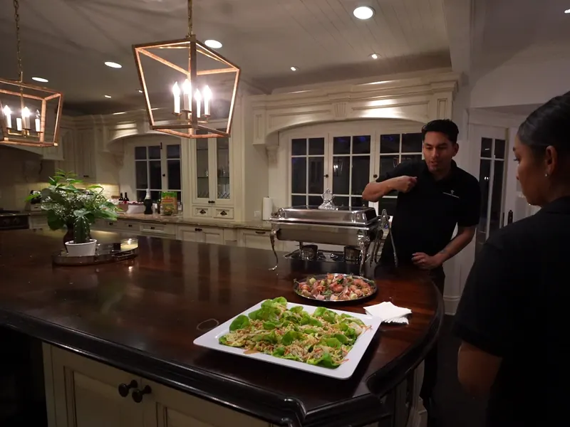 Catering staff finishing platters of appetizers on a kitchen island before a Pleasanton party