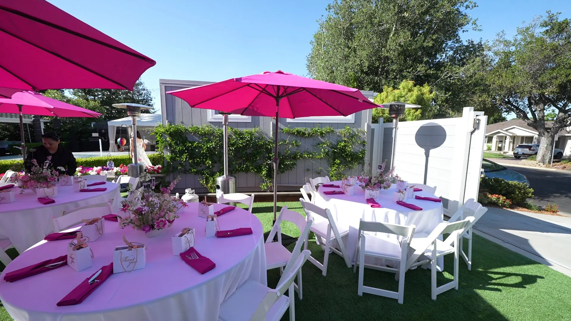 Round tables with pink linens, napkins and market umbrellas set for a San Ramon backyard party