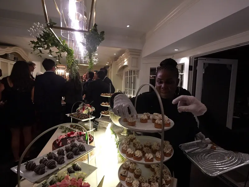 Gloved attendant refreshing a tiered dessert display at a Tri-Valley event