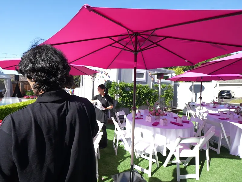 Backyard reception in Pleasanton with white folding chairs, round tables and market umbrellas