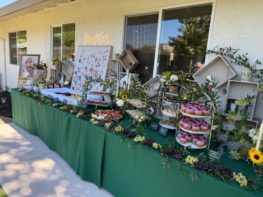 Shower sweets and grazing display with iced cupcakes, grapes and berries softened by fresh blooms and neutral linens — shower florals for San Ramon catering
