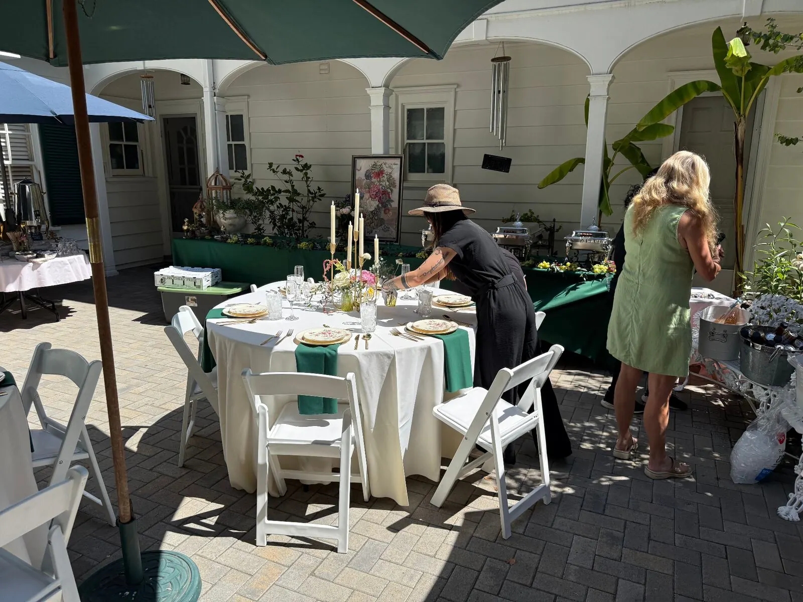 Courtyard rounds in emerald linen with rented glassware and settings accented by compact floral centerpieces — courtyard floral styling for Danville catering