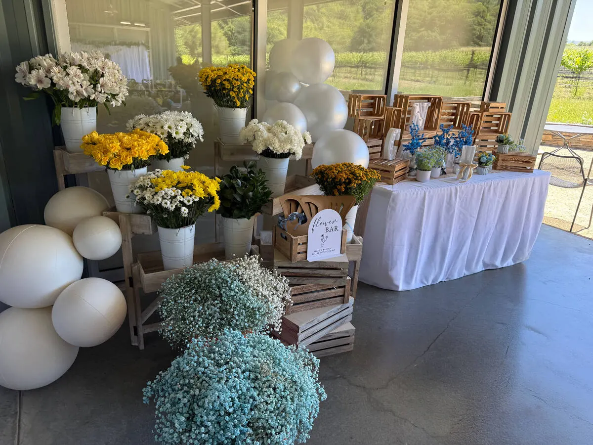 Bloom bar stocked with yellow roses, daisies and baby's breath alongside ribbon and paper so guests can wrap their own bouquets — bloom bar experience from Sunol catering