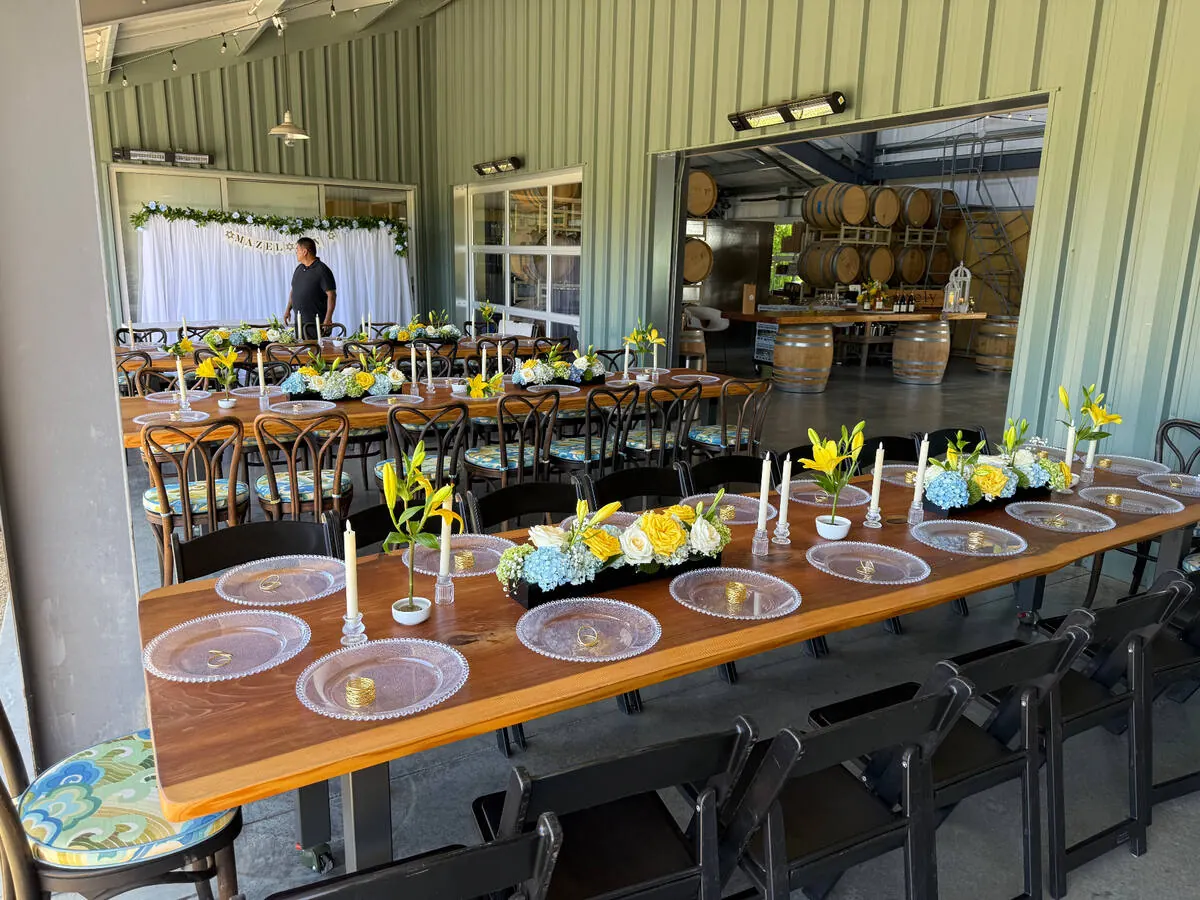 Banquet table carrying lily, hydrangea and rose arrangements between slim tapers down its full length — centerpiece design for Tri-Valley catering receptions