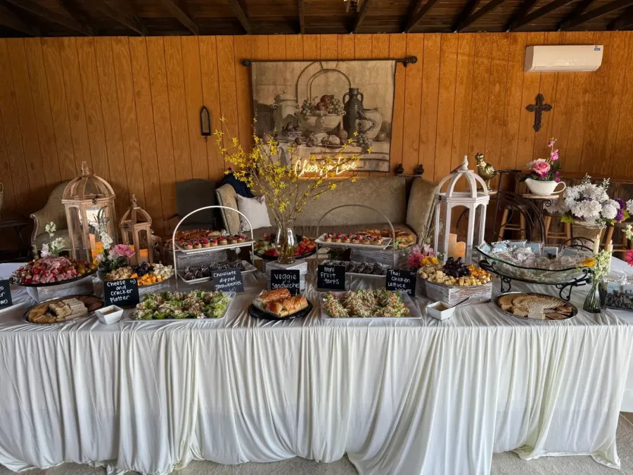 Grazing table of charcuterie, tea sandwiches and fruit tarts punctuated by low garden arrangements — floral-styled grazing service from Livermore catering