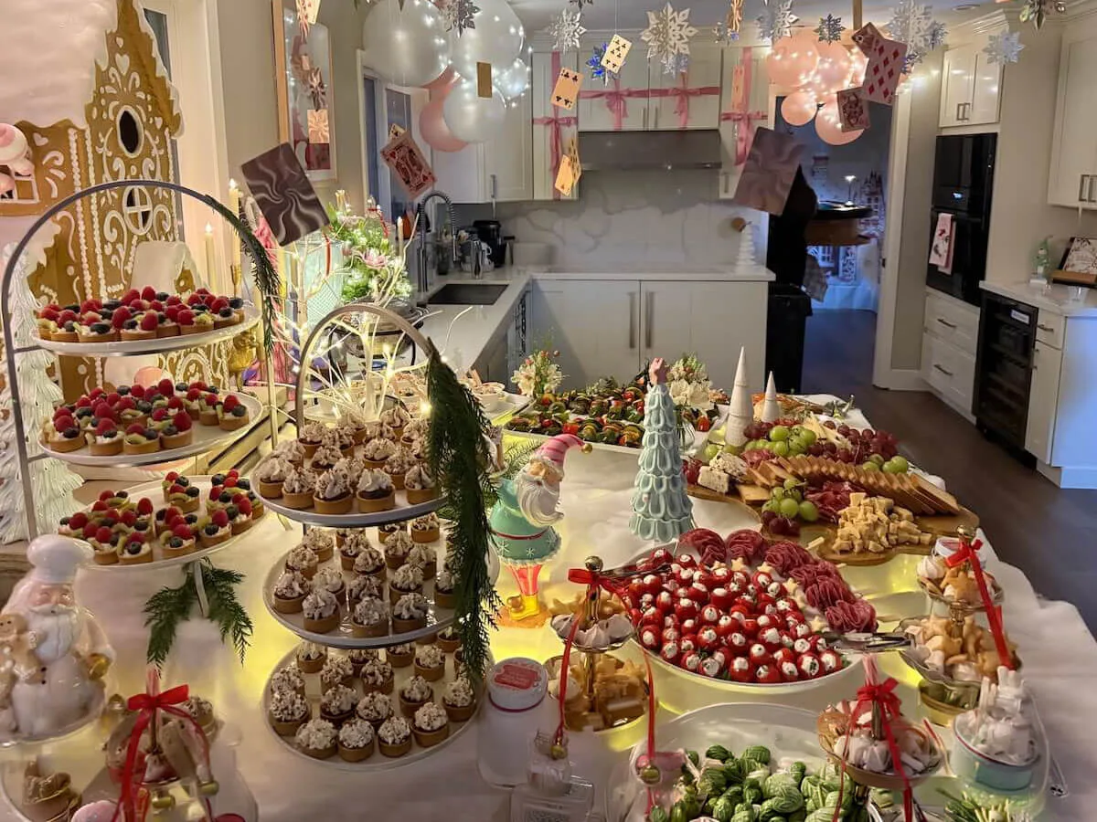 Themed party tablescape of tiered tarts, cupcakes and charcuterie finished with pastel balloons and blossom accents — floral party styling from Dublin catering