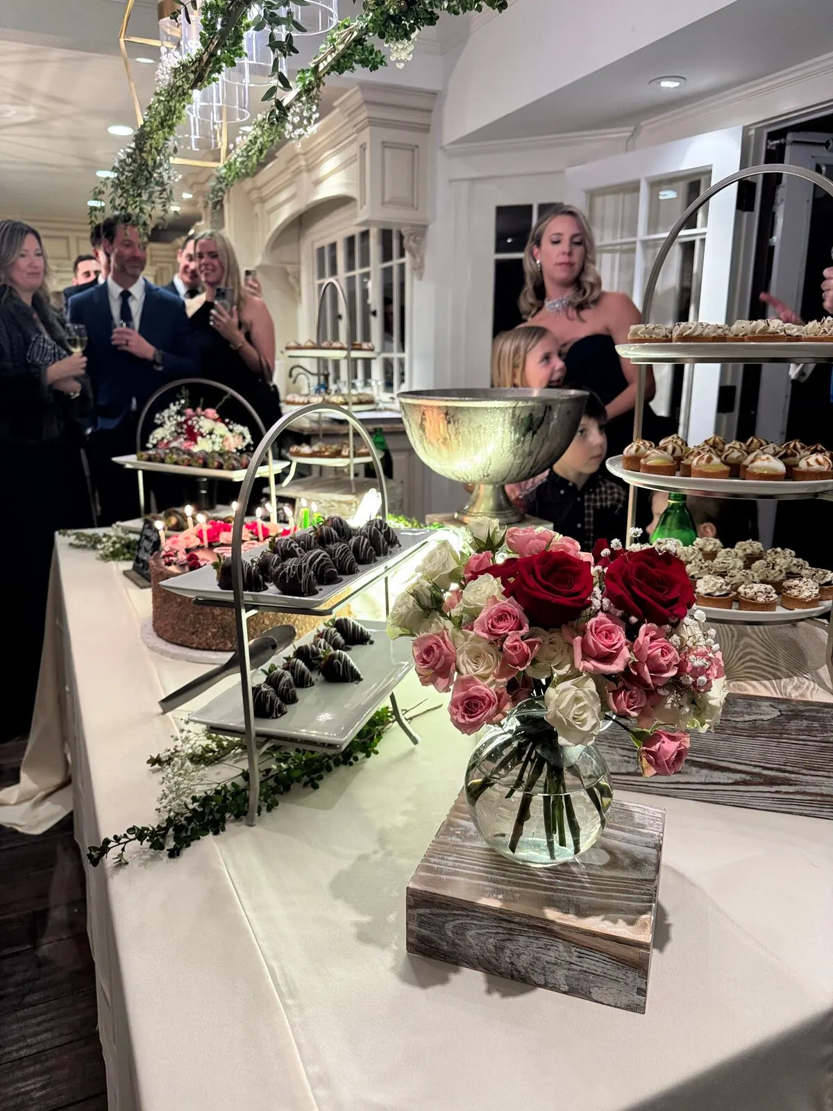 Reception sweets table of chocolate-shelled berries and petite pastries surrounded by fresh garden roses — wedding dessert florals for Pleasanton catering receptions